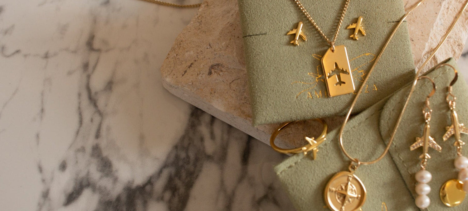 Gold aviation jewelry set including necklace, earrings, and pendant on a green jewelry box with a marble background.