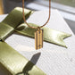Gold rectangular necklace with a runway and airplane silhouette