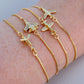 A close-up of a person's wrist wearing four delicate gold chain bracelets, each adorned with a small airplane charm.